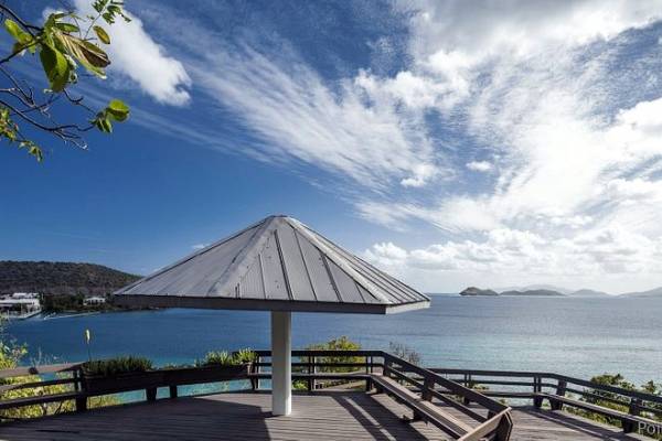 Scenic overlook at Point Pleasant Resort in St. Thomas, U.S. Virgin Islands, featuring a gazebo-style pavilion on a wooden deck with panoramic views of turquoise Caribbean waters, surrounding islands, lush tropical vegetation, and a partly cloudy blue sky.