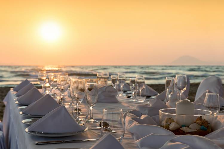 Elegant table setting for a large group on the beach at sunset