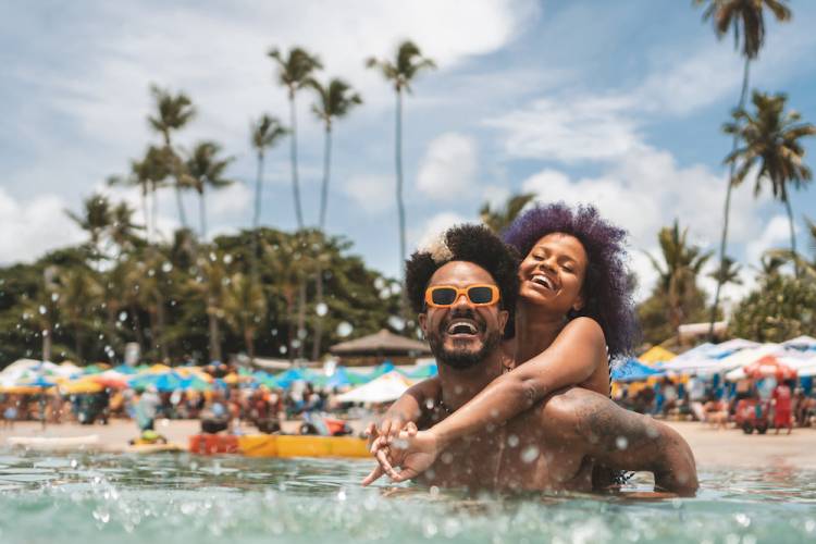 two people in the ocean with palm trees in the background